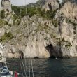 In de rotskliffen van Capri zitten grotten. Er vaart net een bootje in