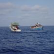 De migrantenboot met links een vissersboot uit Gozo