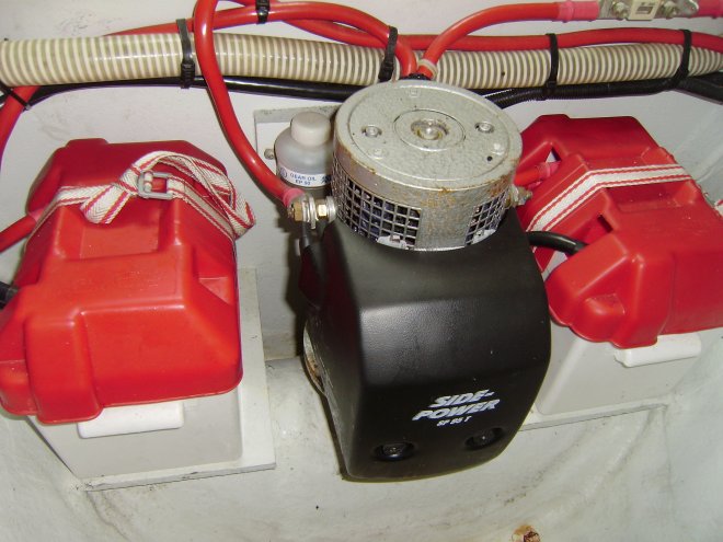 De ruimte voorin de punt van de boot, onder het bed.Tussen de beide accu´s staat de boegschroefmotor. Links ervan een flesje waarop Grease staat. Dat zit er nog in