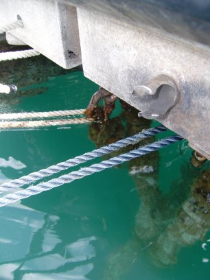Onze landvasten hebben we vastgemaakt aan de dikke schakels van de ankerkettingen van de steiger. Daarboven zie je de finaal doorgescheurde RVS-bout. De dikke ring waar de lijnen eerst aan vastzaten is verdwenen
