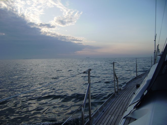 Vanachter een wolkenbank tovert de opgaande zon een fluwelig licht over de zee