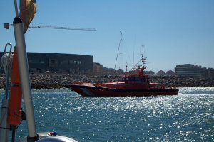 De reddingsboot sleept (langszij) een zeiljacht binnen