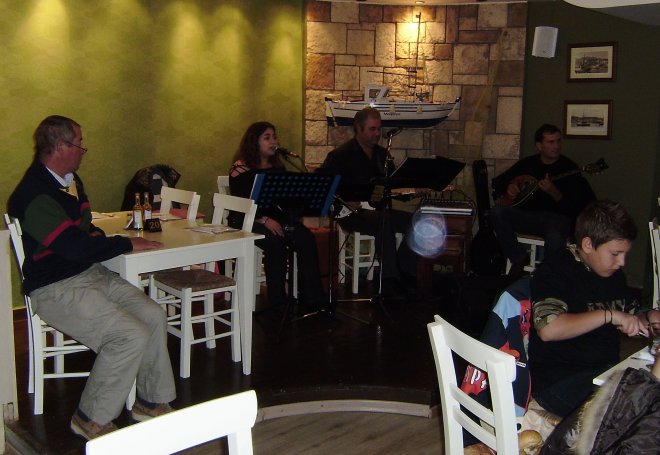 Geert (l) kijkt in Restaurnat Mouragio de kunst van de bouzouki af