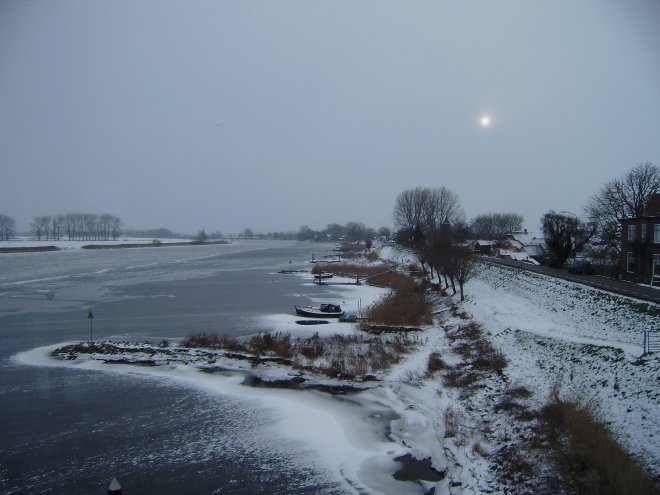 Ons uitzicht over de rivier vanaf de ontbijttafel. Een fletsbleke zon probeert door de grijze sneeuwlucht te breken
