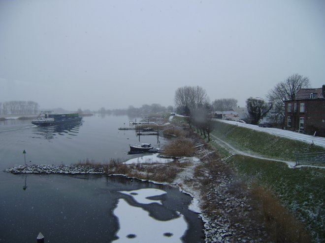 Vanochtend sneeuwt het. Een containerschip vaart de rivier op. Aan de gastensteiger in de verte ligt een zeiljachtje