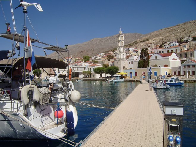 Dulce aan de steiger in de baai van Chalki. Op de achtergrond de orthodoxe kerk met de opvallende klokkentoren