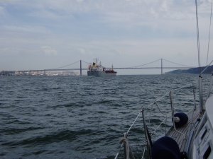 De Taag voor Lissabon, een coaster loopt ons voorbij. In de verte de Ponte de 25 de Abril