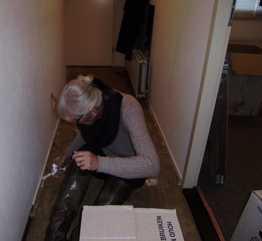 Ans verft de donkerbruine plinten in de gang wit. Rechts kijk je in onze toekomstige slaapkamer.