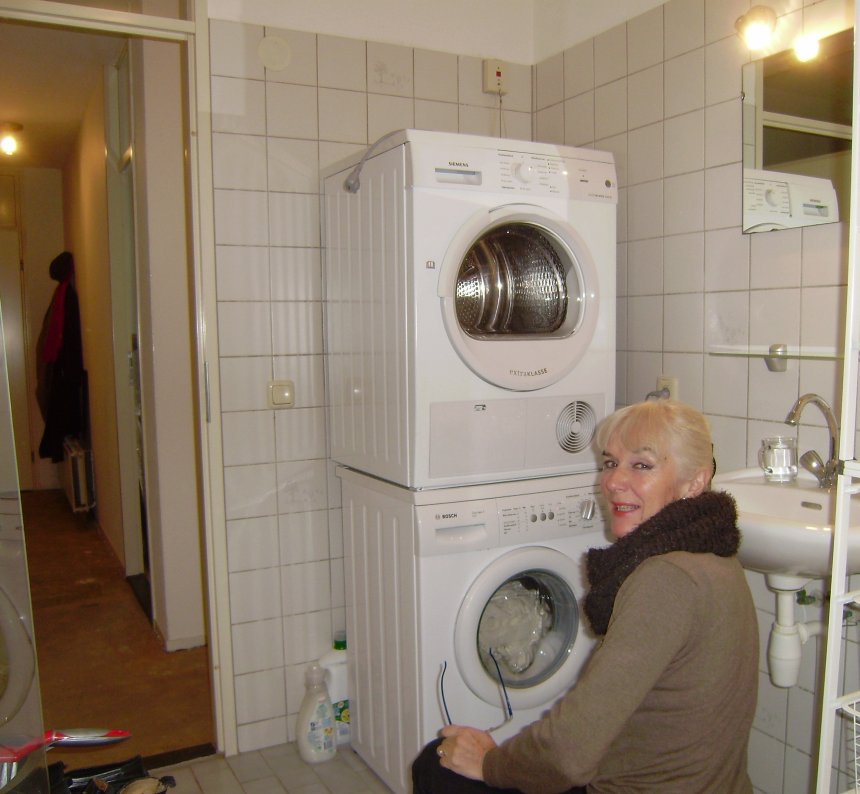 De nieuwe wasmachine met de -droger erop, in de badkamer