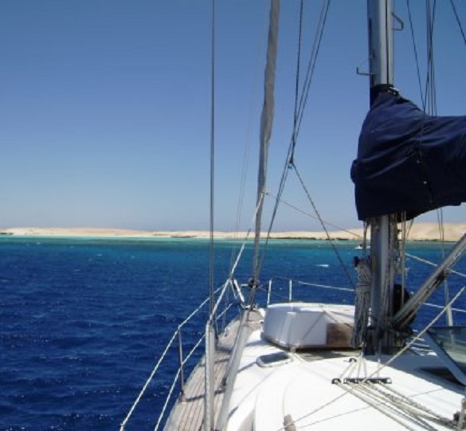 Geankerd bij Bluff Point. De prachtige lichtblauwe rand is de kraag van koraalrotsen om het eiland