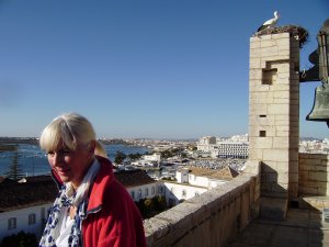 Faro. Hier is veel te zien. Op de eeuwenoude toren van de kathedraal Sé do Faro. Rechtsboven een ooievaar op zijn nest. Daarnaast de klokken. Achter Ans de stad en de lagunes. Beneden het plein met de sinaasappelbomen