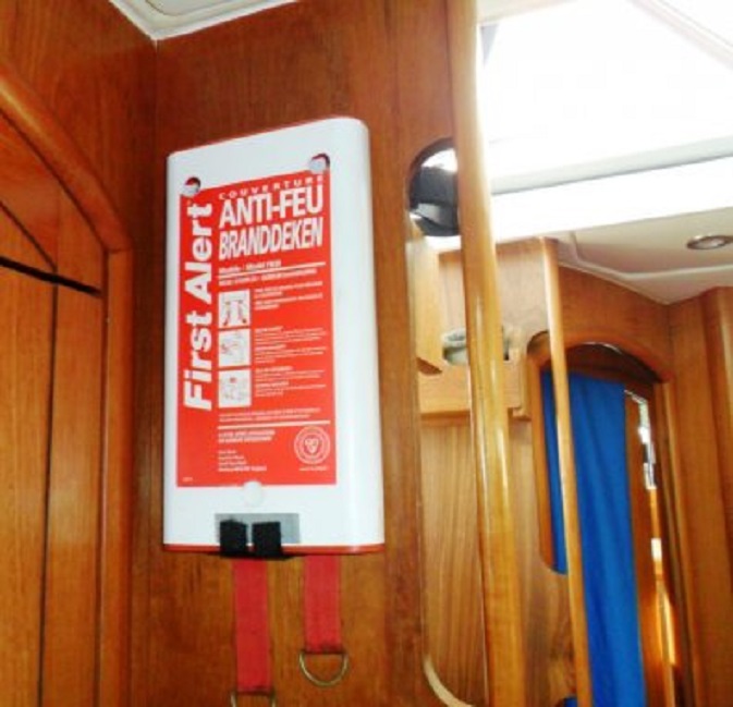 De muurvast bevestigde houder van de branddeken in de kombuis,tegenover het gasfornuis