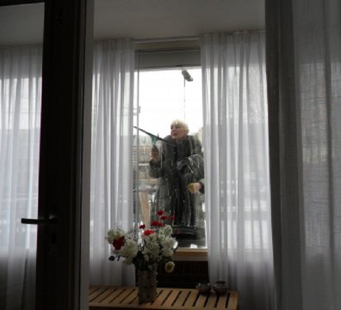 Van achter mijn bureau zie ik mijn geliefde de ruiten van de schuifpui reinigen