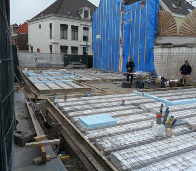 De vloer van het BlueBandhuis is gelegd. Eronder gaat de middeleeuwse waterput schuil, iets boven de buizen die uit de vloer steken