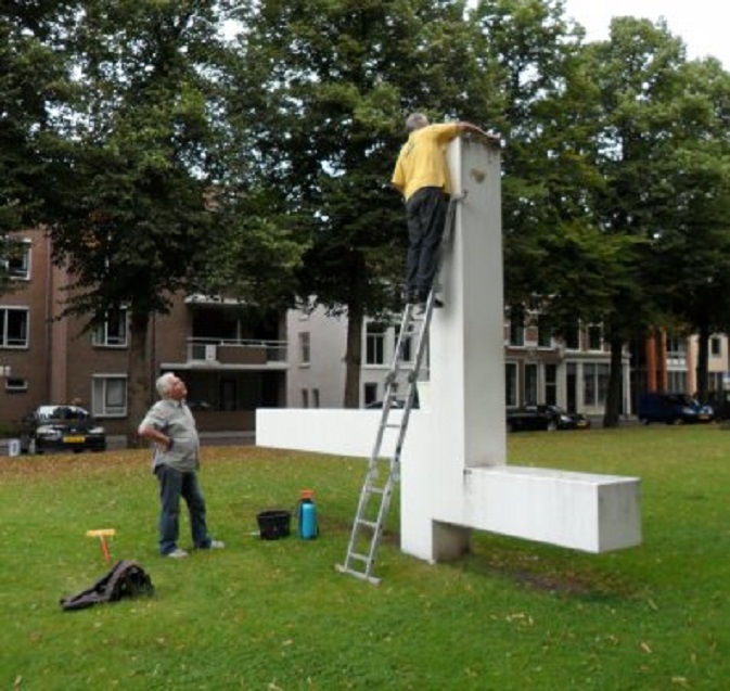 Leden van buurtvereniging KNAKE maken het beeld van Ad Dekkers op de Kalkhaven schoon