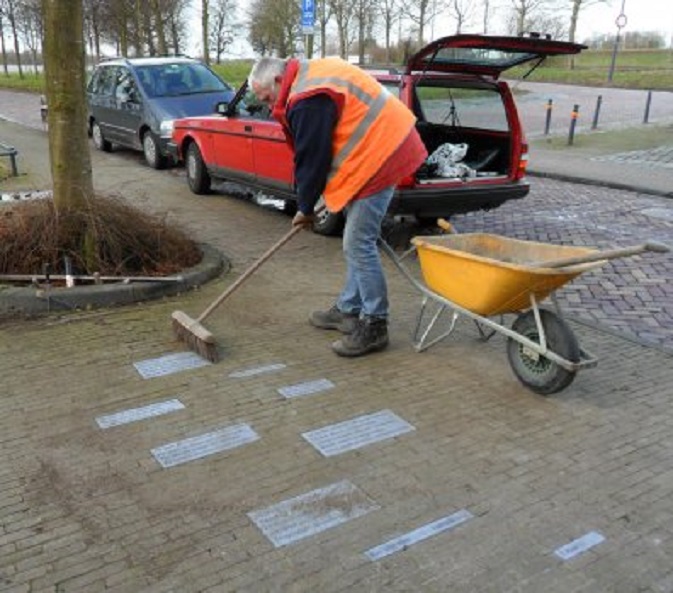 De stratenmaker veegt de stenen met het gedicht van K. Michel schoon
