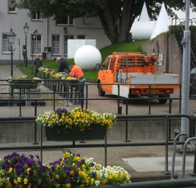 Gemeentewerklieden vervangen de bakken met volop bloeiende violen door bakken met pieterende geraniums