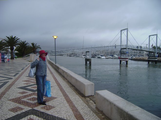Op de boulevard zien we de rolwolk van een opkomend onweer naderen. Rechts de voetgangersbrug, daarachter de haven