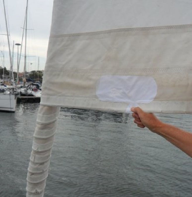 De gerepareerde genua: de losgewaaide zoom over een meter vastgenaaid en de gaten geplakt