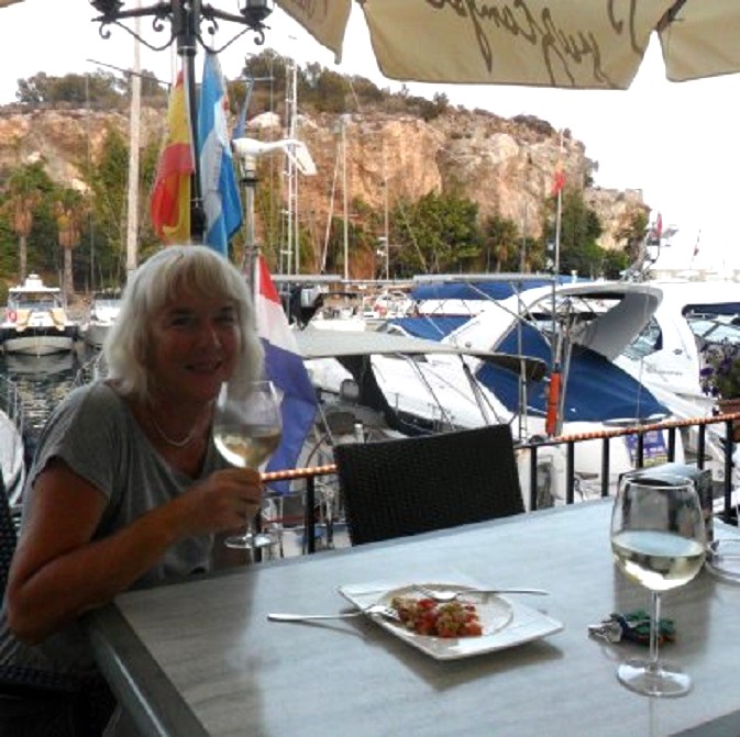 Aan de witte wijn in Marina del Este. Achter Ans de boot en daarachter de rots tussen het haventje en de zee
