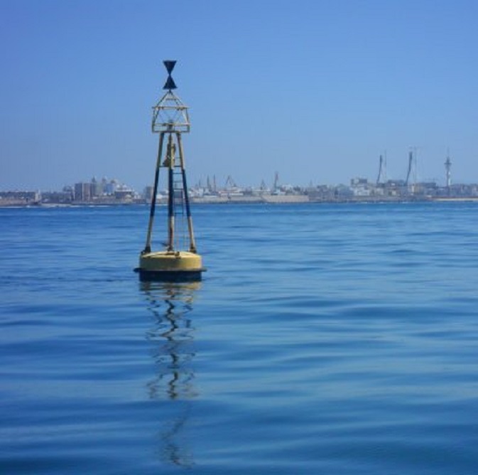 Westkardinale boei bij de ingang van de Baai van Cádiz. De skyline van de stad op de achtergrond