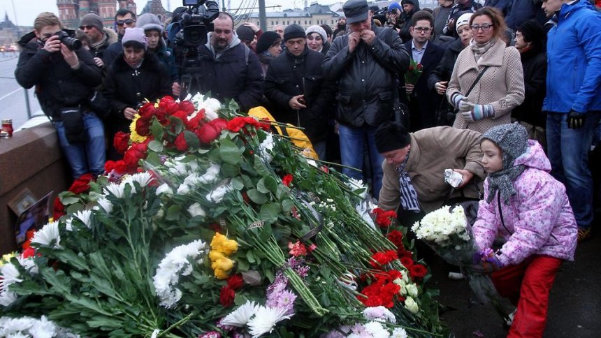 Bloemen hopen zich op op de brug waar Boris Nemtsov vannacht doodgeschoten werd. Op de achtergond het Kremlin.