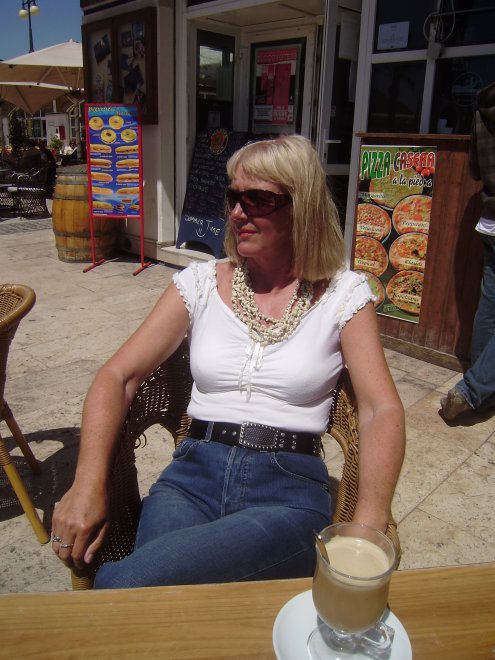 Terrasje bij de haven. Het lijkt windstil, maar pas op: een minuut later waait het bord boven de rechterschouder van Ans met veel geraas om