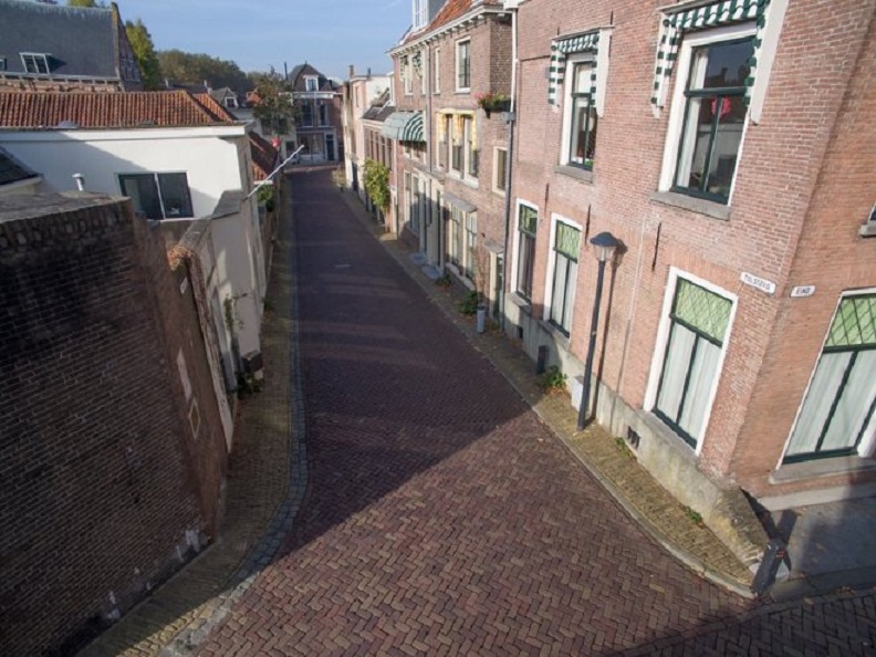 Grappig, op Google Earth staat een lege Tolsteeg. Je ziet dat er nauwelijks trottoirs zijn. De foto is genomen vanaf de onoverzichtelijke kruising met 't Eind bij de coupure in de stadswal.