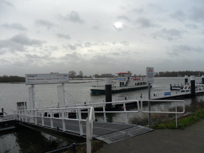 De pont van Woudrichem legt aan op Buiten de Waterpoort. De uiterwaard op de achtergrond staat onder water.