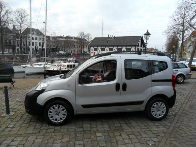 Ons nieuwe autootje. Ans met bos bloemen achter het stuur. Dulce links op de achtergrond.in de haven.