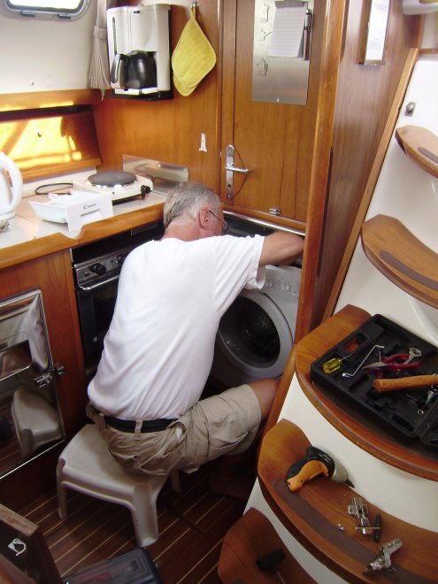 Zwoegen aan de wasmachine. Die is kapot. het paneel met bedieningsknoppen is naar binnen geschoten.