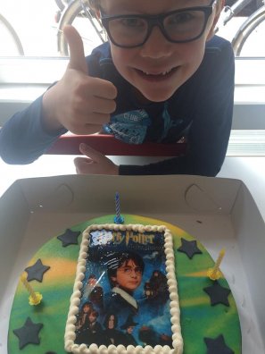 De jarige Thijs bij zijn Harry Potter-verjaardagstaart. De zes kaarsjes heeft hij al uitgeblazen.