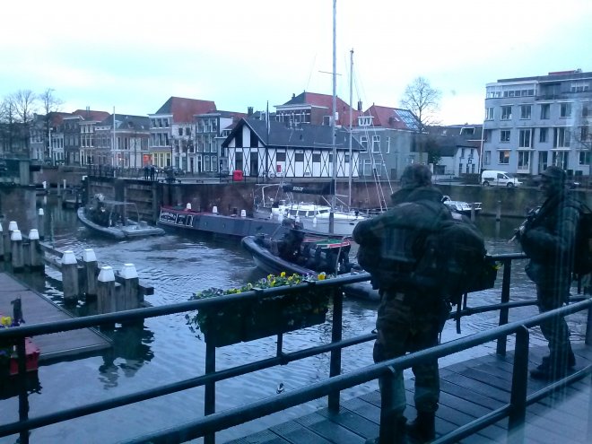 Bewapende mariniers posteren zich op de loopbrug rond ons huis. In de haven varen zware rib's.
