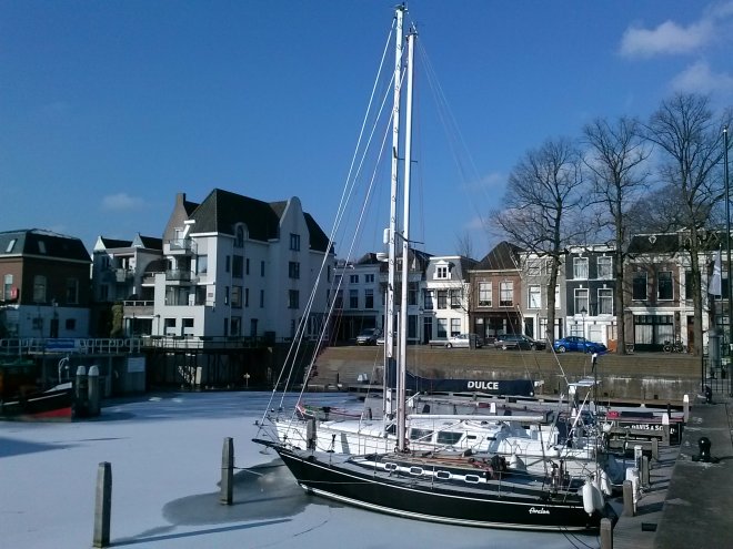 De ingevroren overwinteraars in de havenkom. Op de hoek op de achtergrond ons huis.