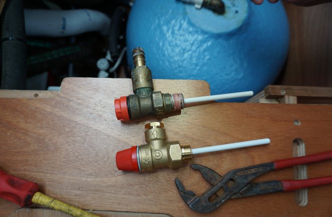 Twee overdrukventielen. De onderste is de nieuwe, de andere lekt door verkalking, waardoor het niet meer sluit. Op de achtergrond de boiler.