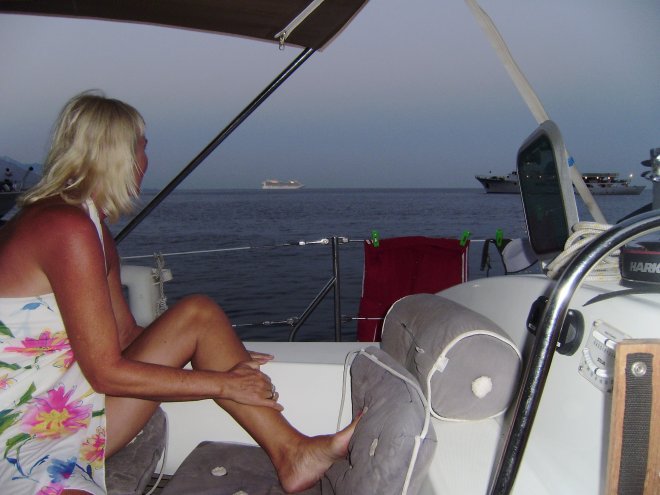 Voor anker bij Capri. Op zee vaart een groot, verlicht cruiseschip voorbij