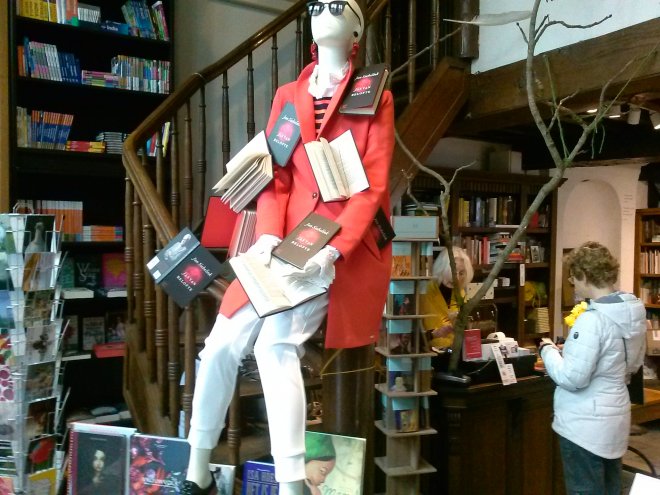 De etalagepop in Boekhandel De Mandarijn. Rechts achter de kassa boekhandelaar Emmy.