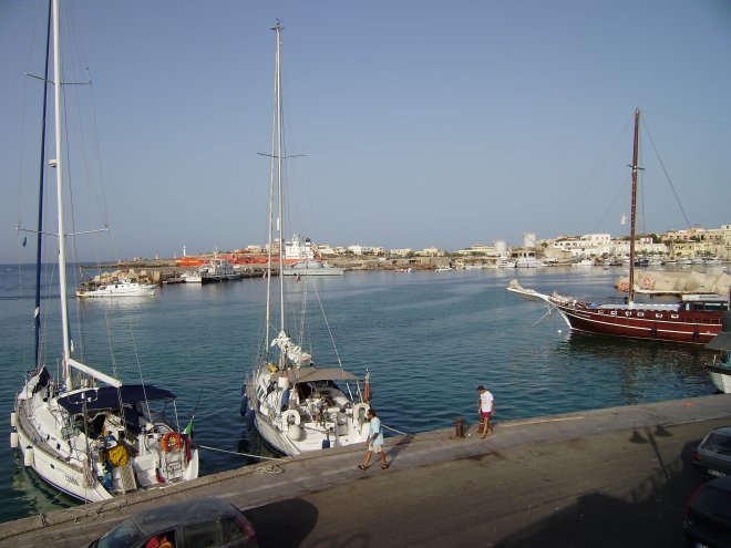 Dulce (midden) in de haven van Lampedusa. Aan de overkant de kade van de kustwacht, waar de zwarte migranten aan wal worden gebracht