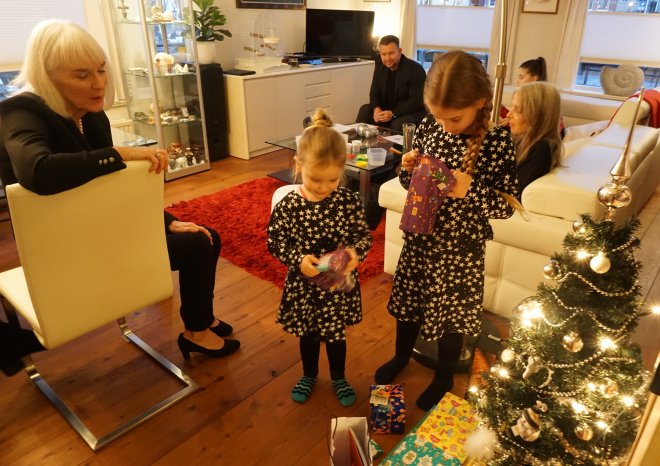 Kerstcadeautjes uitpakken. Op de voorgrond Anna, Lina- mae en Vajèn. Achtergrond Michel, Esri en Barbara