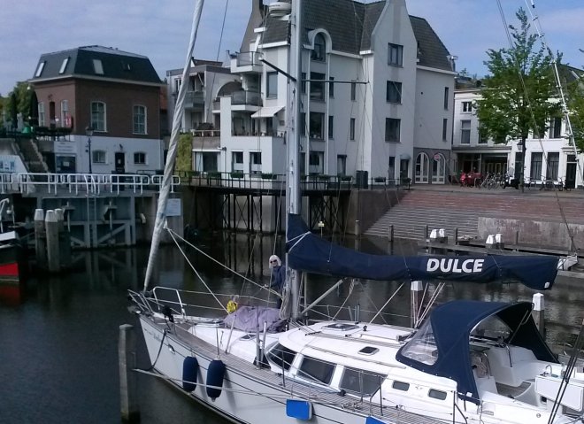 Spuiten, boenen en poetsen van het dek. Op de achtergond ons huis.