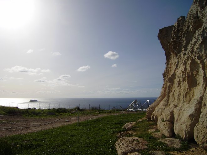 Rechts de zwaar geërodeerde kalsteenmuur van de tempel van Hagar Qim, in de verte links Filfla