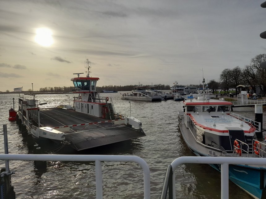 De veerpont van Brakel ligt werkeloos aan het remmingwerk voor de Lingesluis. Rechts de watertaxi, Verderop de beide electrische veren.en nog verder een groot cruiseschip. Daarachter de gezwollen Merwede.