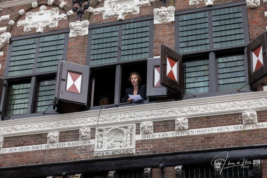 Tjitske Buwalda leest het volk in de Gasthuisstraat gedichten voor uit het raam van Boekhandel De Mandarijn (foto Hans de Heus)