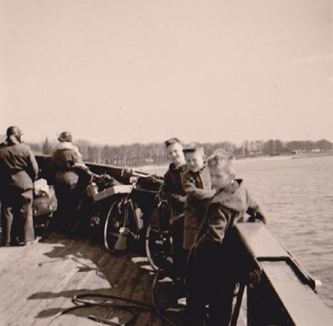 Veerpont over de Merwede, 1956. V.r.n.l. mijn broertje Wiebe, Jitse Kingma en ikzelf. Wie goed kijkt ziet links tussen de twee militairen bij de boeg het puntje van de Gorcumse kerktoren.