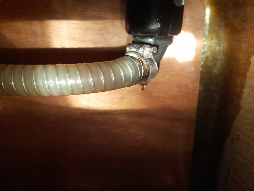 Een stroom druppels valt uit de onderkant van het voetpompje bij het aanrecht.