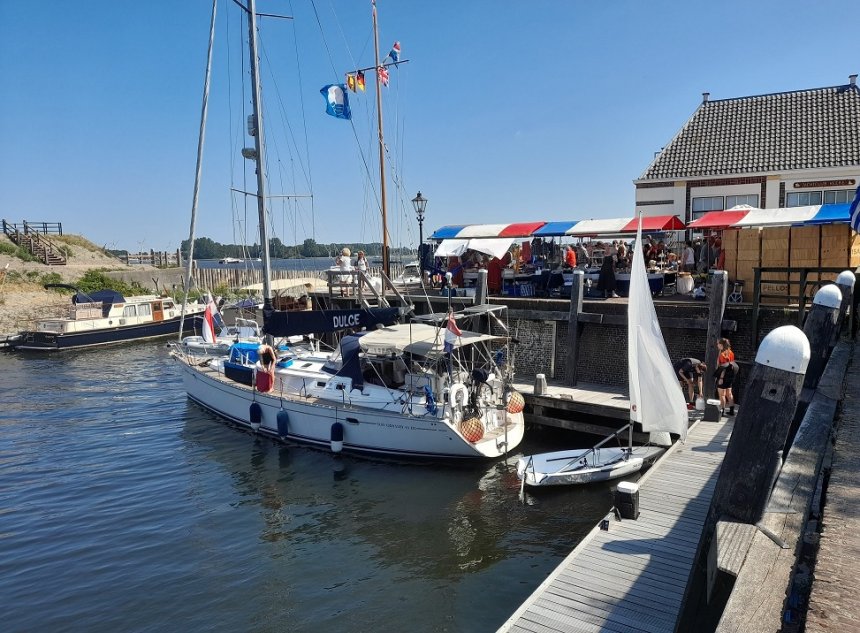 Veere. In de ochtend is het nog rustig. Op de kade de kramen van de Historische Markt. 's Middags arriveren heel wat boten. Rechts de Jachtclub en in de verte het Veerse Meer.