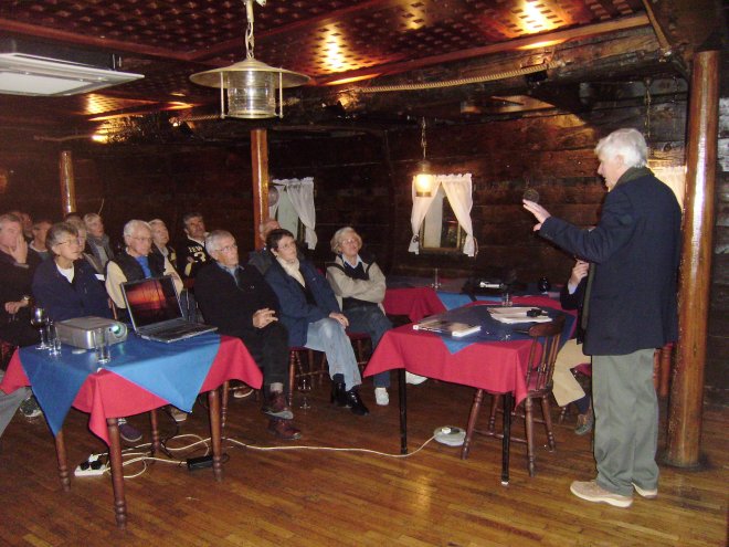 Lezing van Graham Hutt (rechts) met lichtbeelden in het ruim van de Black Pearl